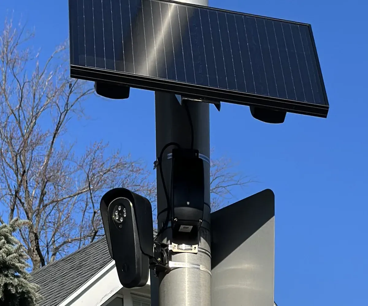A Flock Safety camera mounted below a rectangular solar panel.